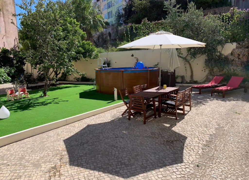 a table and chairs with an umbrella and a lawn at Graça Palace with Private Pool Garden in Lisbon