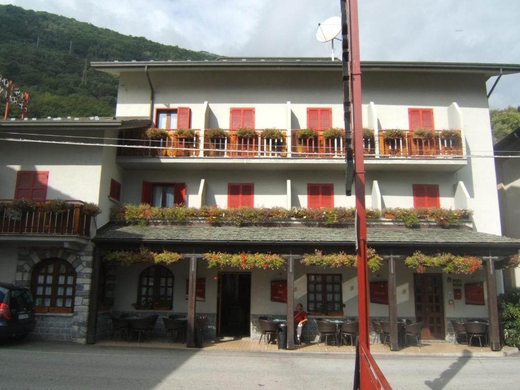 een gebouw met rode luiken en tafels en stoelen bij Hotel Berlinghera in Sorico