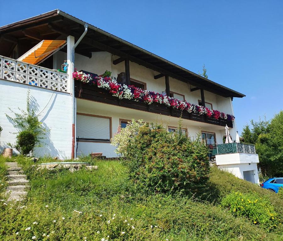 uma casa com uma varanda com flores em Ferienwohnung Gipfelblick em Oberreute