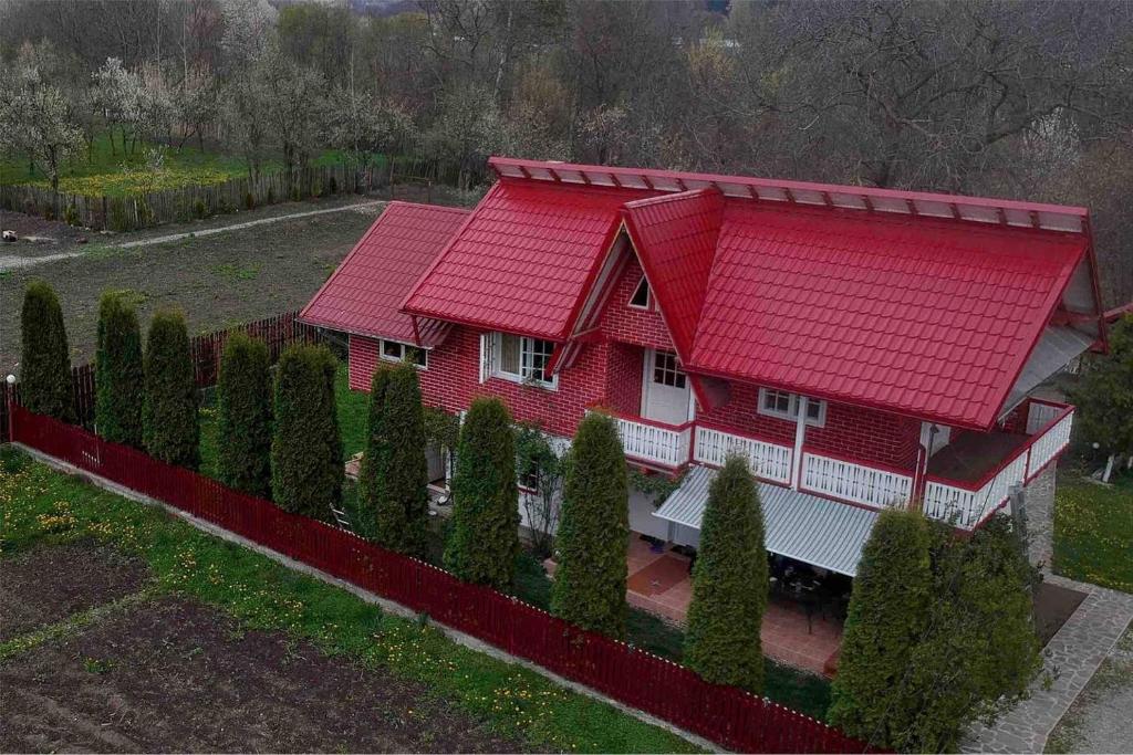 una casa roja con techo rojo y algunos árboles en PENSIUNEA STEFANIA, en Brebu Mînăstirei