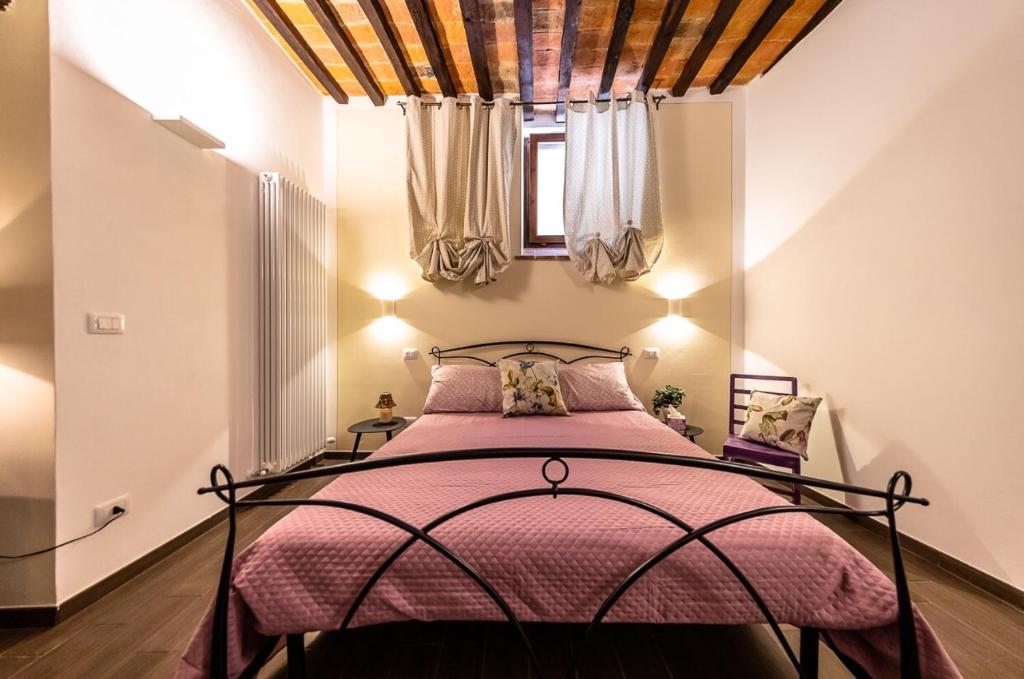 um quarto com uma cama com uma colcha rosa em Appartamento Da Lucia em Città della Pieve