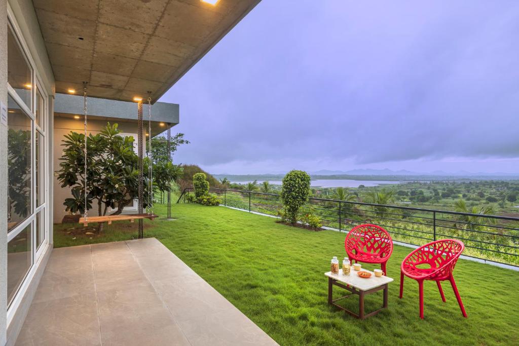 un patio con 2 sillas y una mesa en el césped en SaffronStays Serenity, Igatpuri en Igatpuri