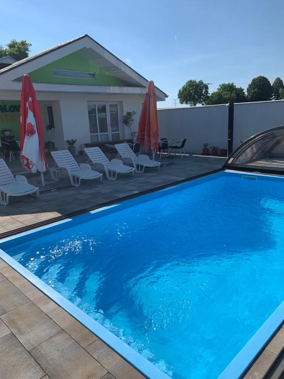 uma grande piscina azul com cadeiras e guarda-sóis em Bungalovy Classic em Podhájska