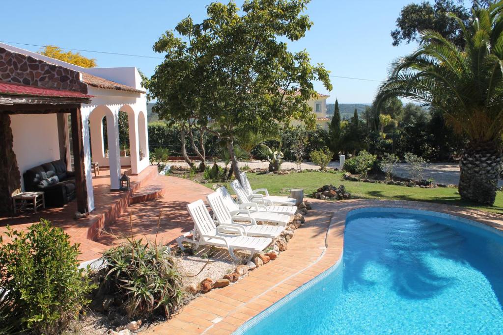 een zwembad met witte stoelen en een huis bij Villa Alegria in Lagos