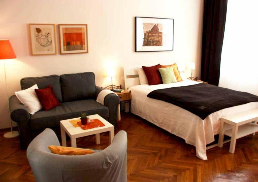 Cosy Appartement close to City في فيينا: غرفه فندقيه بسرير واريكه
