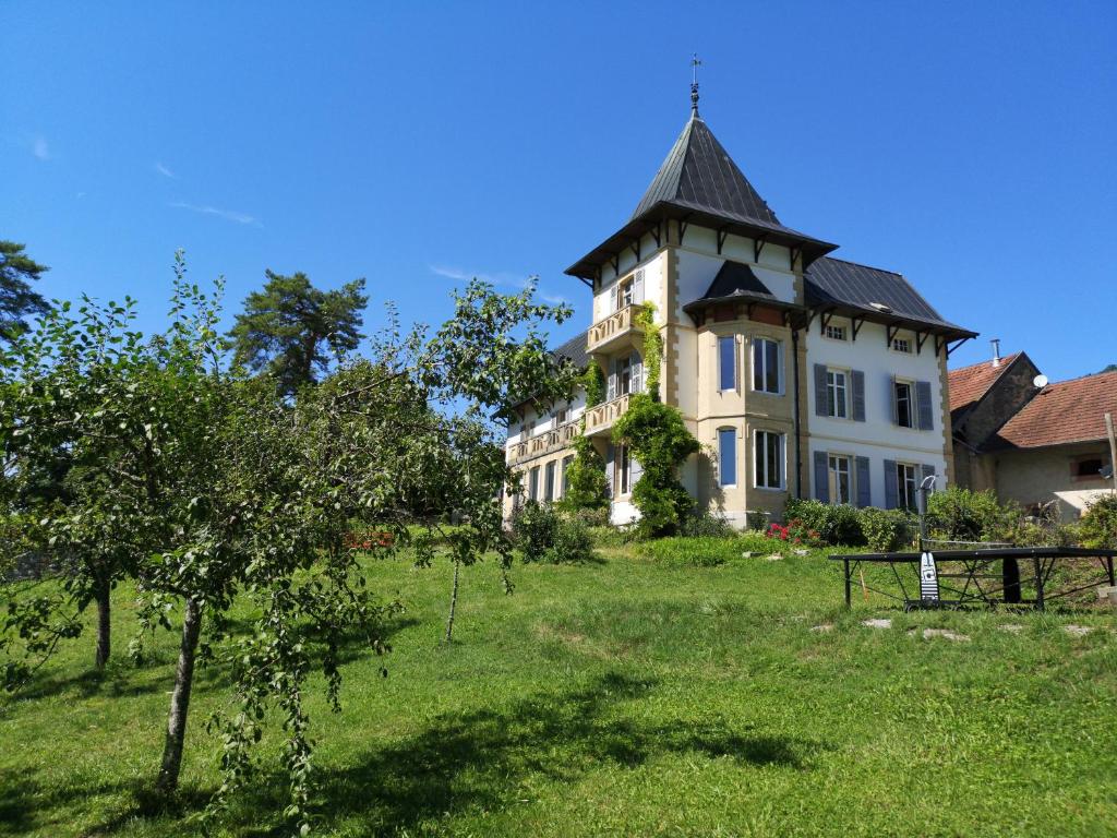 duży budynek z wieżą na szczycie pola w obiekcie Villa Meyriem w mieście Mouthier-Haute-Pierre