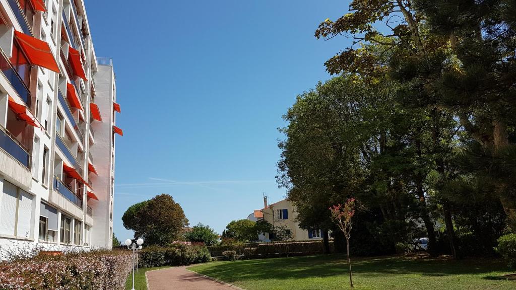 un bâtiment avec une cour herbeuse à côté d'un bâtiment dans l'établissement COSY HELIOS, à Royan