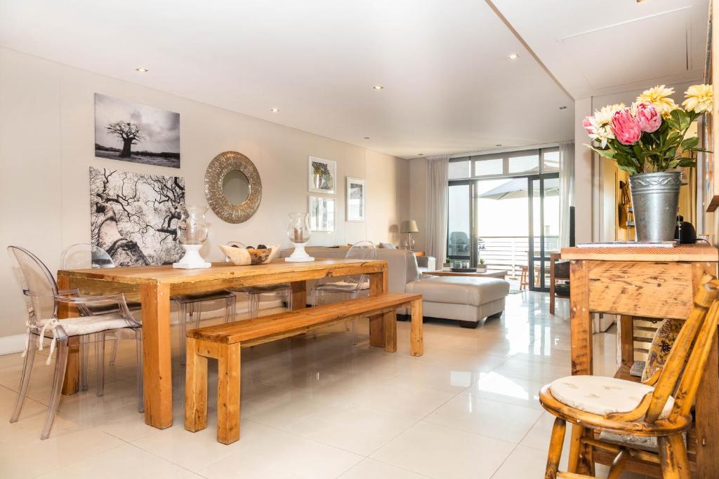 uma sala de estar com uma mesa de madeira e cadeiras em Luxury Ocean View 2 Bed Apartment 259 Eden on the Bay, Blouberg, Cape Town em Big Bay