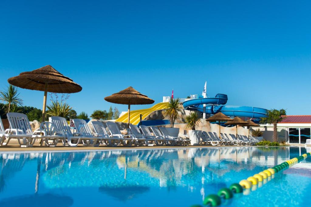 a swimming pool with chairs and a water slide at Camping Officiel Siblu Les Charmettes in Les Mathes