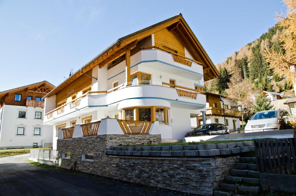 a house in the mountains with a stone wall at Apart Bergblick in Ischgl