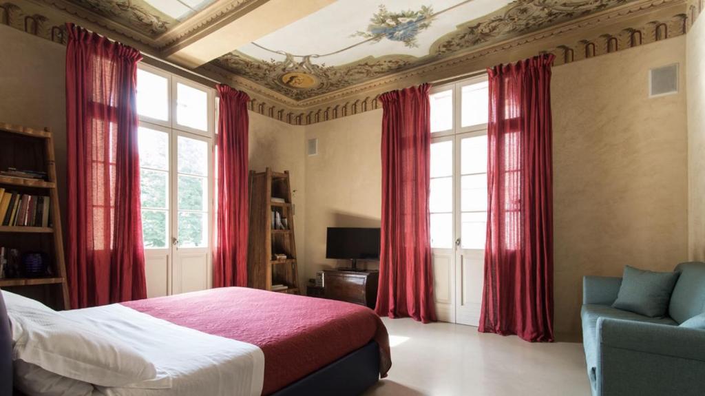 a bedroom with red curtains and a bed and a chair at Domus Aurea in Carpi