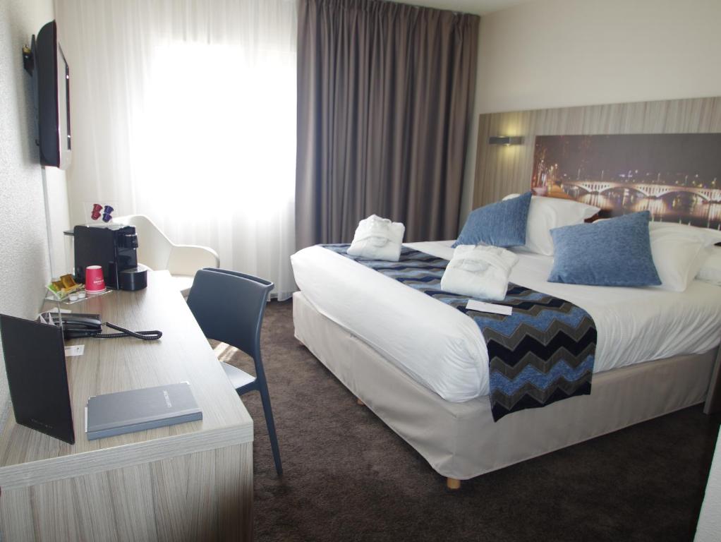 um quarto de hotel com uma cama grande e uma secretária em Hôtel Saphir Lyon em Lyon