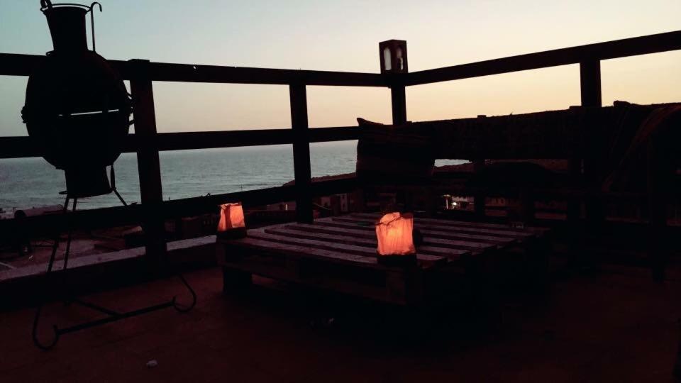 a bench on a deck with the ocean in the background at Imsouane soul lodge in Imsouane