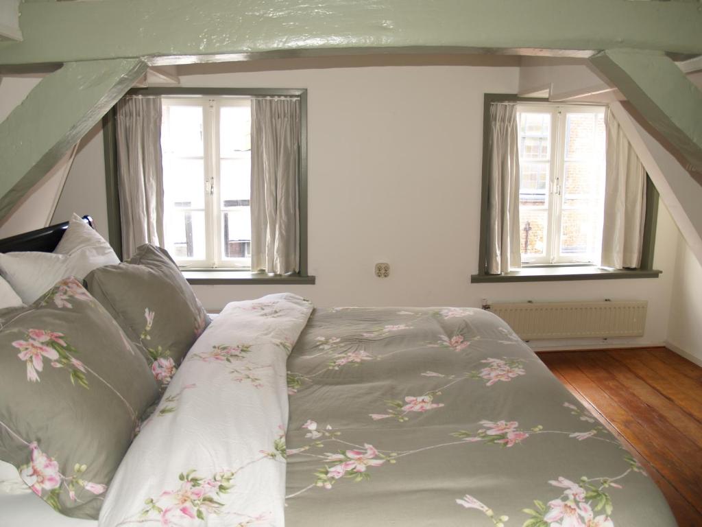 a bed in a room with two windows at Pearl of the Hague - R.Q.C. in The Hague