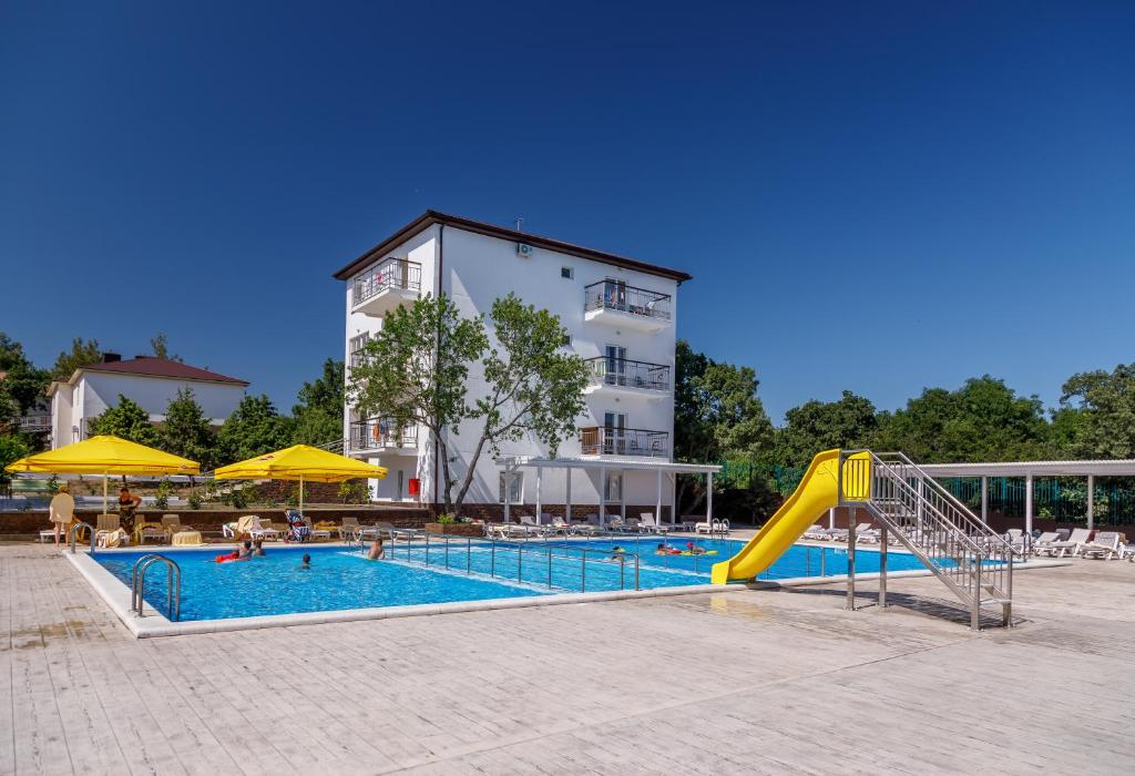 a swimming pool with a slide in front of a building at Talka Village in Divnomorskoye