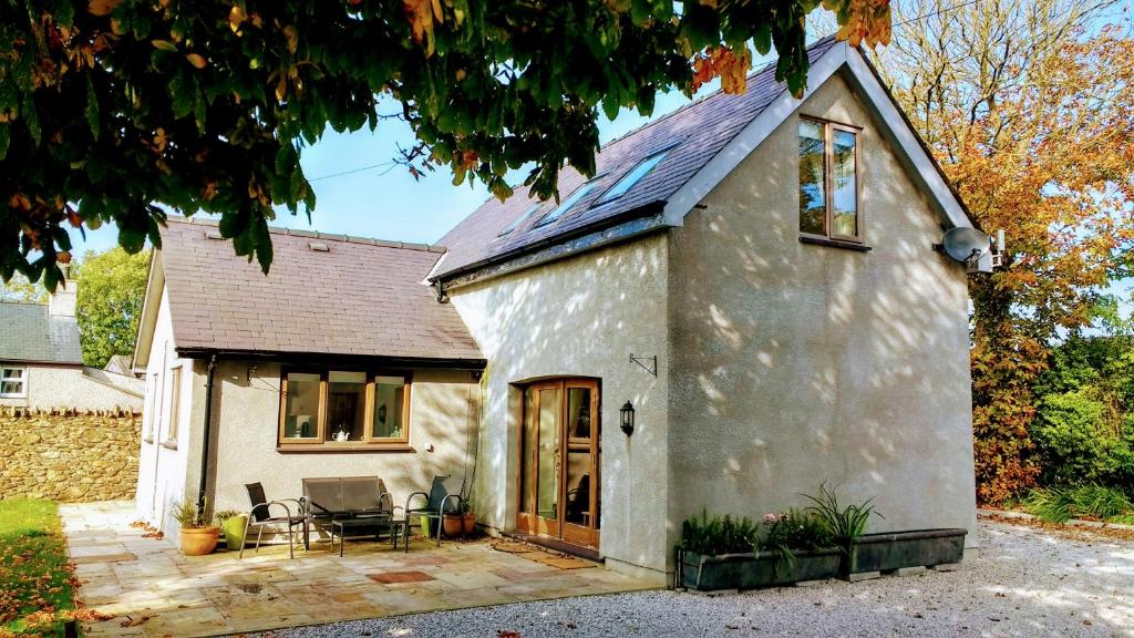 a white cottage with a patio in front of it at Honey Cottage in Amlwch