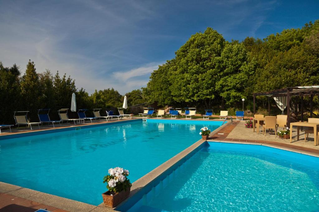 a large blue swimming pool with chairs and tables at Pausania Inn in Tempio Pausania