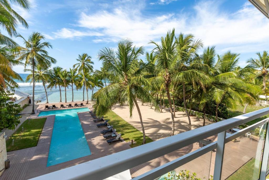 Vom Balkon eines Resorts genießen Sie Strand- und Poolblick. in der Unterkunft Beachfront King Bed Privacyjacuzzifullkitchen in La Puntica de Juan Dolio