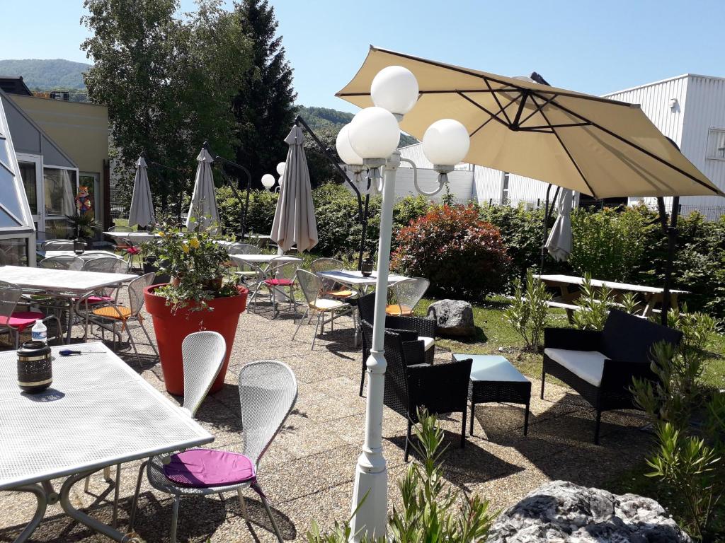 un patio con mesas, sillas y una sombrilla en ibis Grenoble Université, en Gières