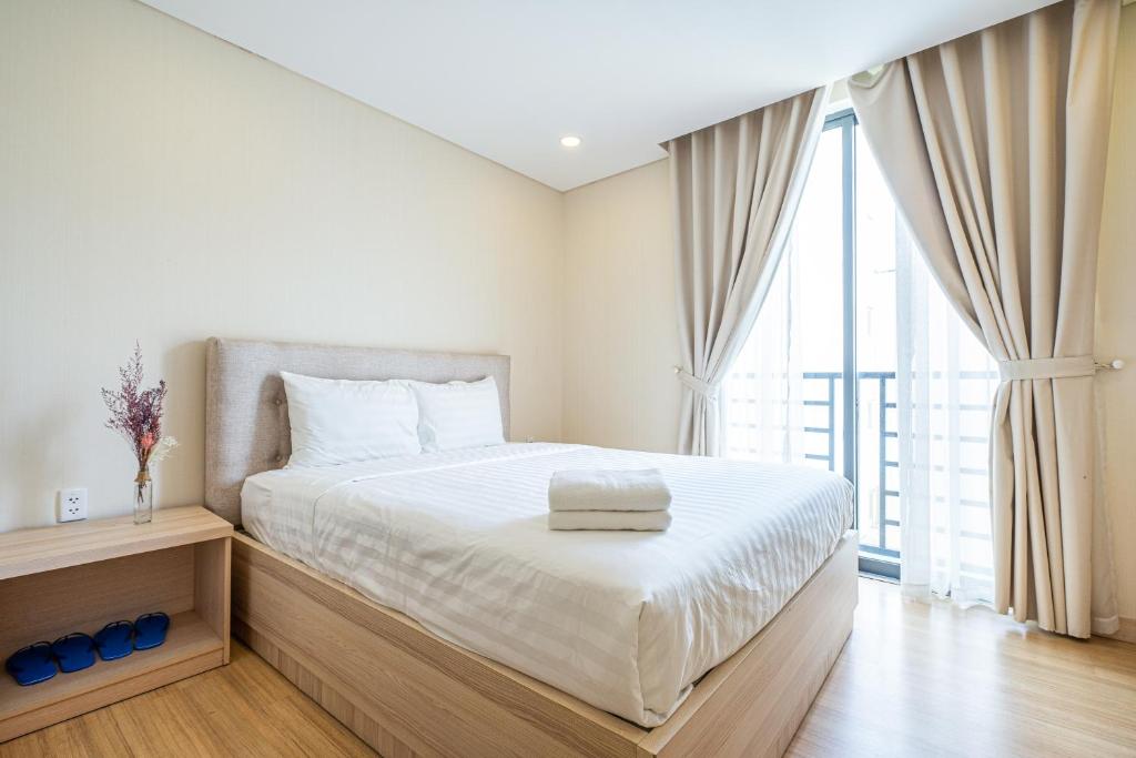 a bedroom with a white bed with a large window at Luxy Park Hotel & Apartments - Notre Dame in Ho Chi Minh City