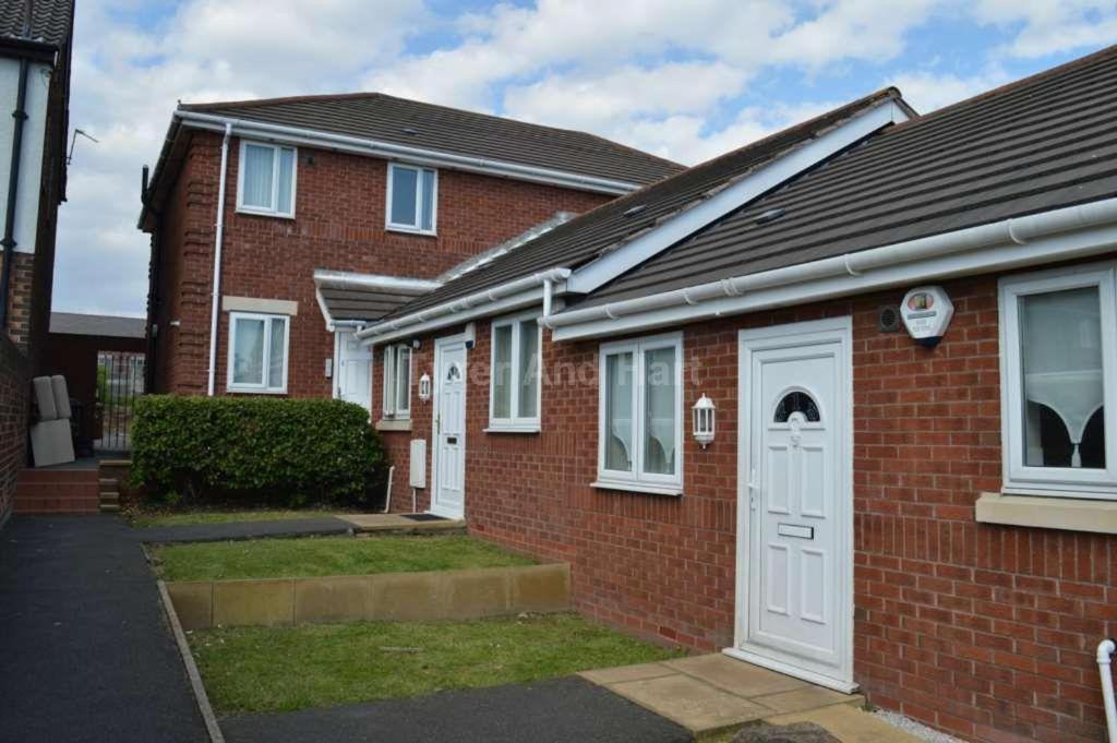 a brick house with white doors and windows at Pinfold Court Apartments in Knowsley