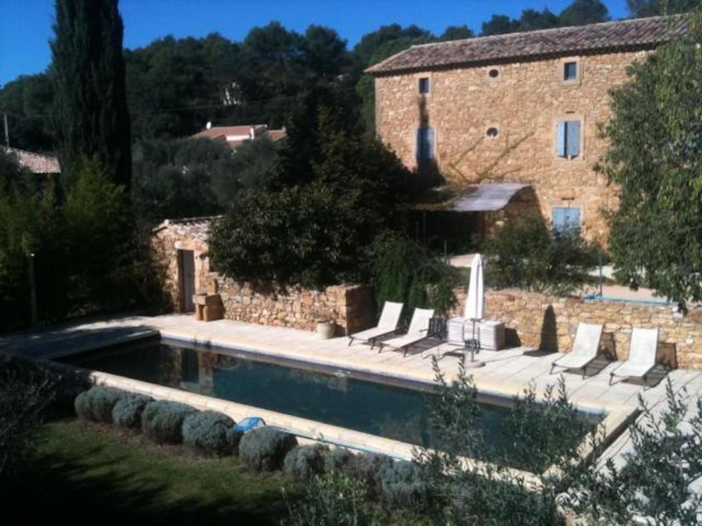Aigaliers的住宿－le mas du cypres, 12 pers et piscine，石头建筑前的游泳池