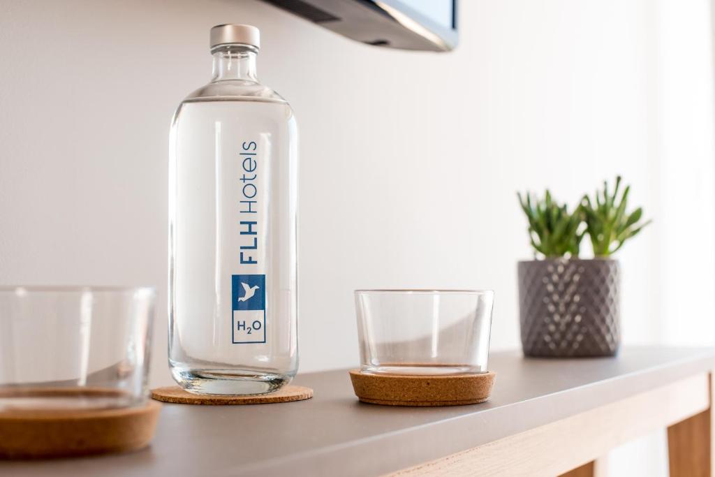 a bottle of water and two glasses on a table at Reserva FLH Hotels Ericeira in Ericeira