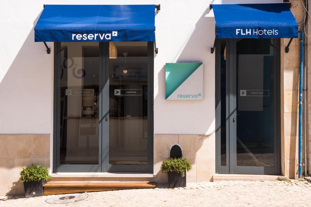 a facade of a store with a blue awning at Reserva FLH Hotels Ericeira in Ericeira