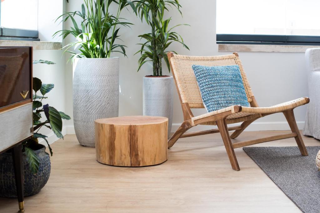 a chair with a blue pillow and a wooden stool at Reserva FLH Hotels Ericeira in Ericeira