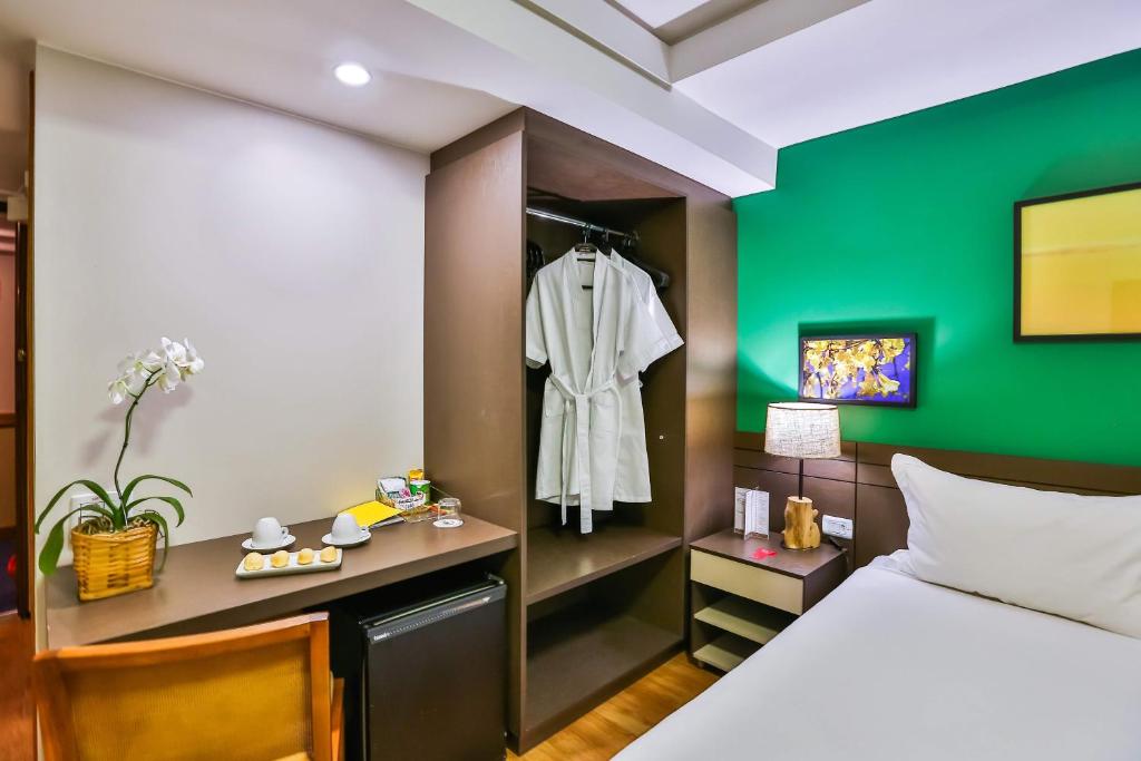 a bedroom with a dresser and a bed at Golden Tulip Goiania Address in Goiânia