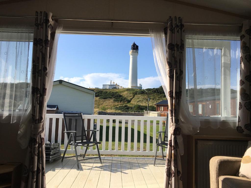 a view of a lighthouse from the porch of a house at 87 Lighthouse View Lodge in Lossiemouth