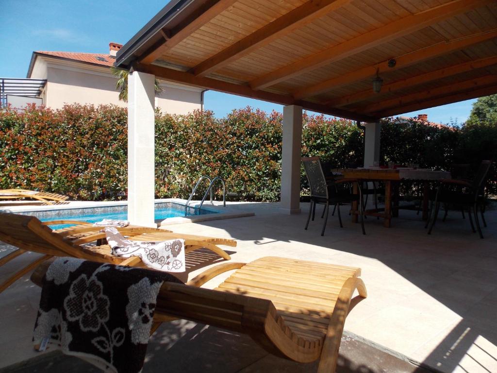 een terras met een tafel en stoelen en een zwembad bij Apartment with private pool in Njivice