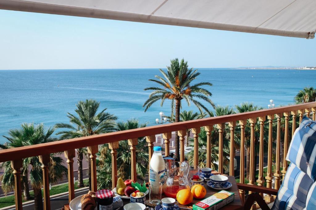 a table on a balcony with a view of the ocean at Promenade des Anglais - Studio suite seaside in Nice