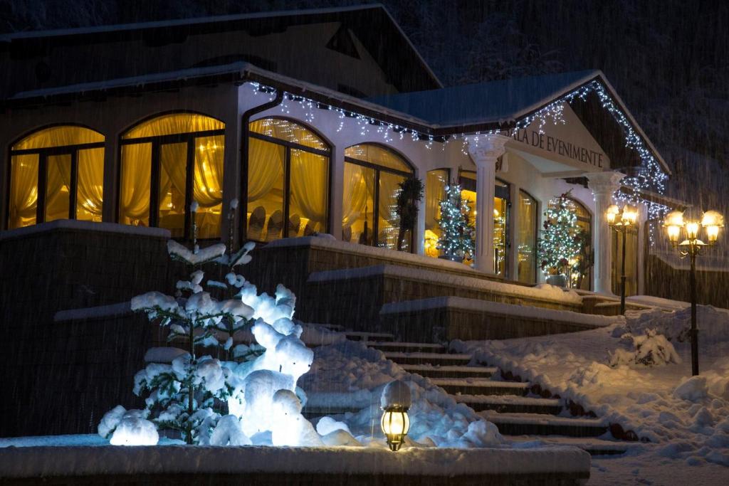 ein Gebäude mit Weihnachtslichtern im Schnee in der Unterkunft Pensiunea Perla Martiniei NSD in Martinie