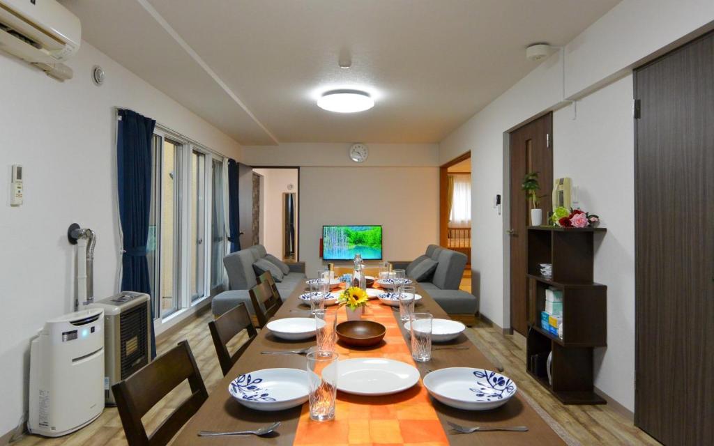 a dining room with a long table with chairs and a television at Sejour Misono / Vacation STAY 4663 in Sapporo