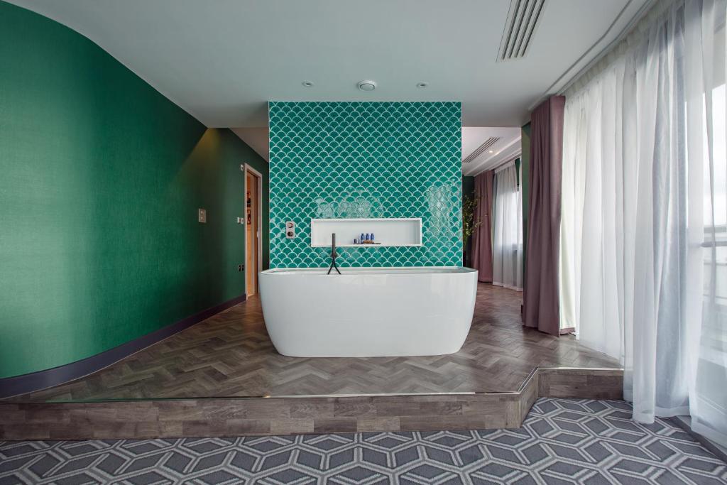 a bathroom with a white tub in a green wall at Waterfront Southport Hotel in Southport