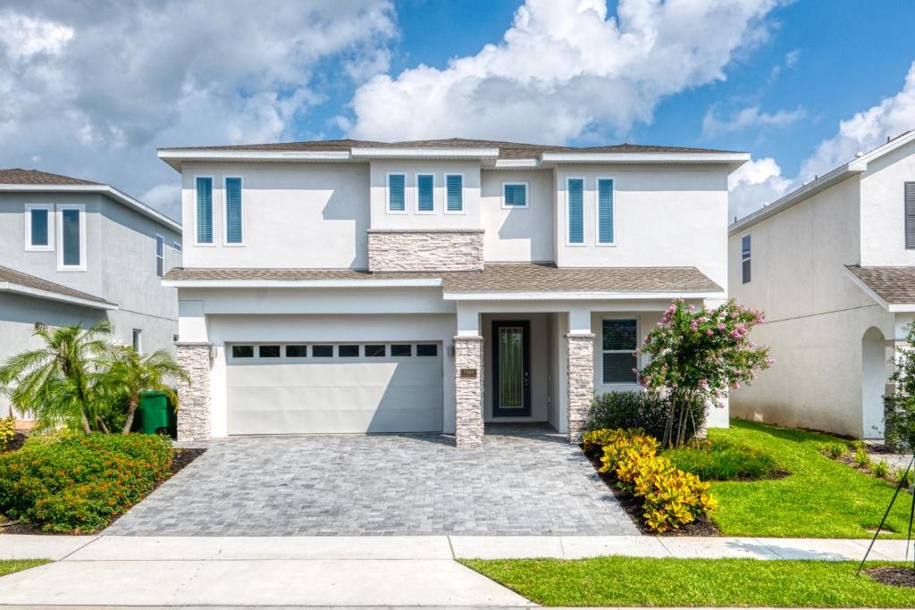 a white house with a garage at Beautiful Home by Rentyl Near Disney with Private Pool, Pool Table & Resort Amenities - 7448M in Orlando