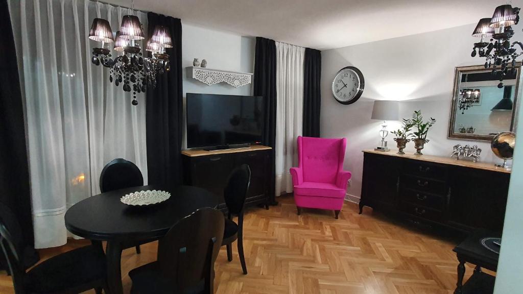 een woonkamer met een tafel en een roze stoel bij Apartament Twarda in Warschau
