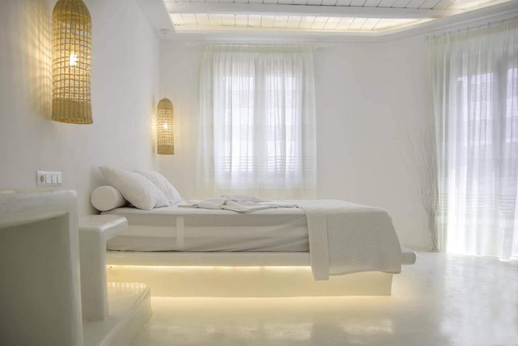 a white bedroom with a bed in a room with windows at Kritamos suites in Iraklia