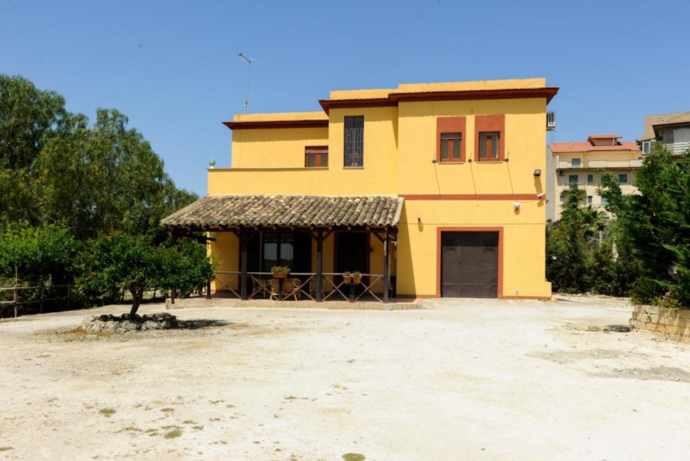 a yellow house with a table in front of it at Il Covo degli Artisti in Campobello di Licata