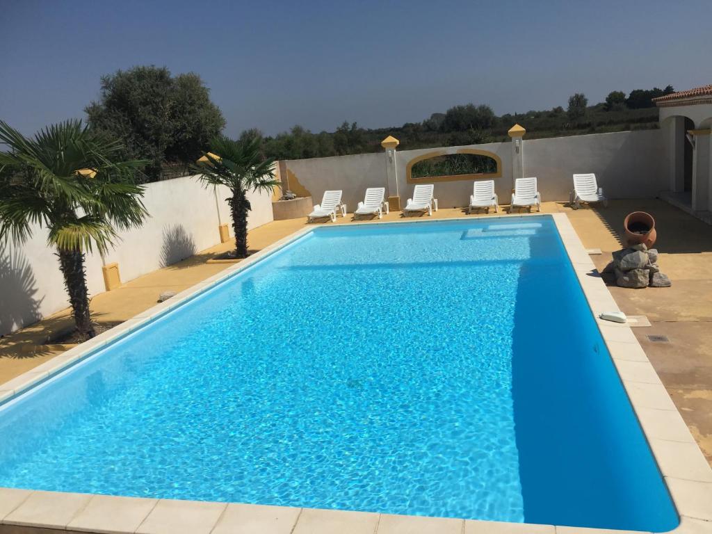 une grande piscine bleue avec des chaises sur la terrasse dans l'établissement EL ROCIO 1 GITES EQUESTRE, à Saintes-Maries-de-la-Mer