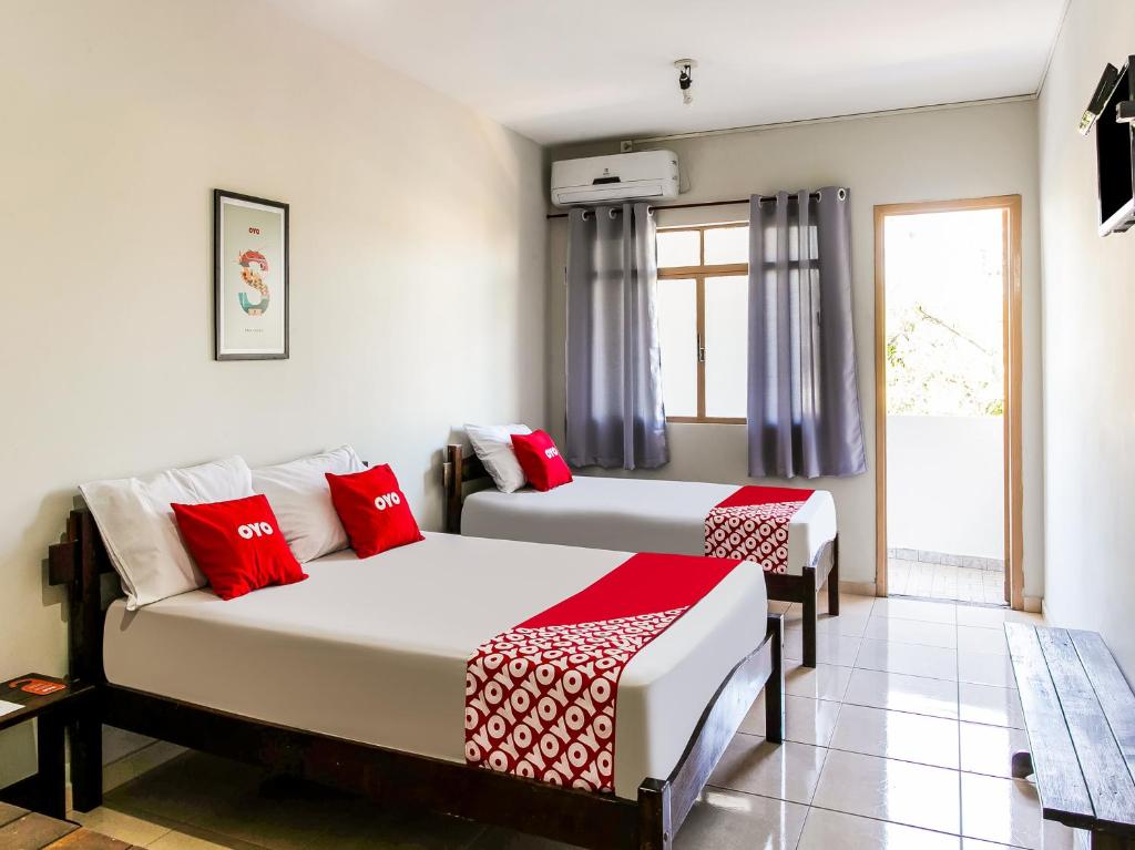 2 camas en una habitación con almohadas rojas y blancas en OYO Hotel Nobrega Aeroporto de Congonhas, São Paulo en São Paulo