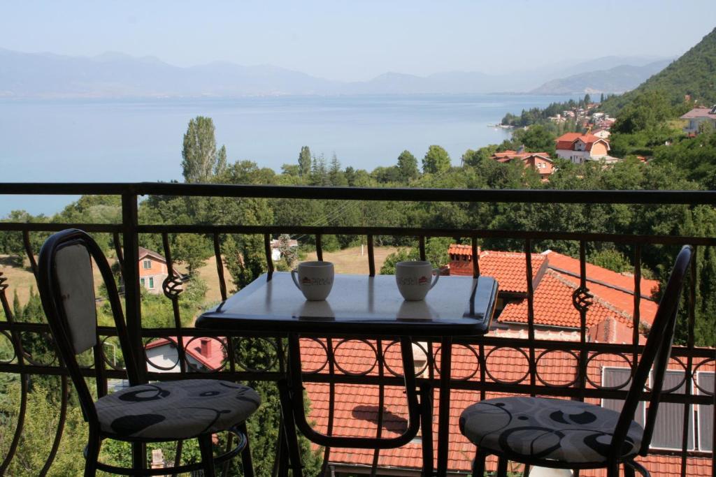 a table with two cups and two chairs on a balcony at Villa Karolina in Ohrid