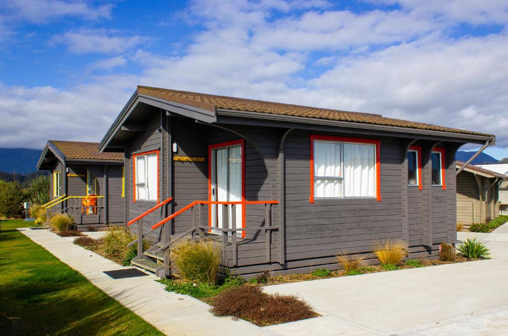 Casa gris con ventanas rojas y entrada en Little Wanganui Hotel en Little Wanganui