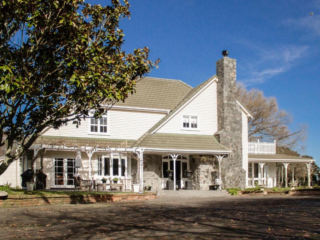 a large white house with a chimney on top at Goodin Country Garden in Okato