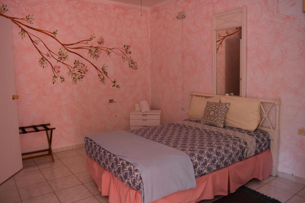 1 dormitorio con 1 cama en una pared de color rosa en Posada del Mar, en La Parguera