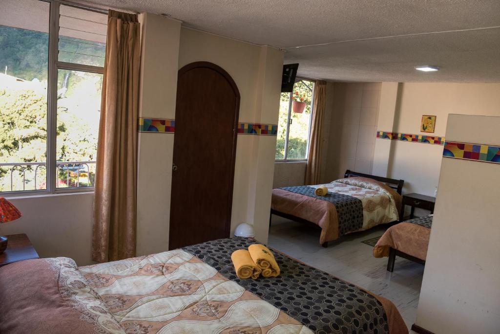 een slaapkamer met 2 bedden en een raam bij Hotel Flor de Oriente in Baños