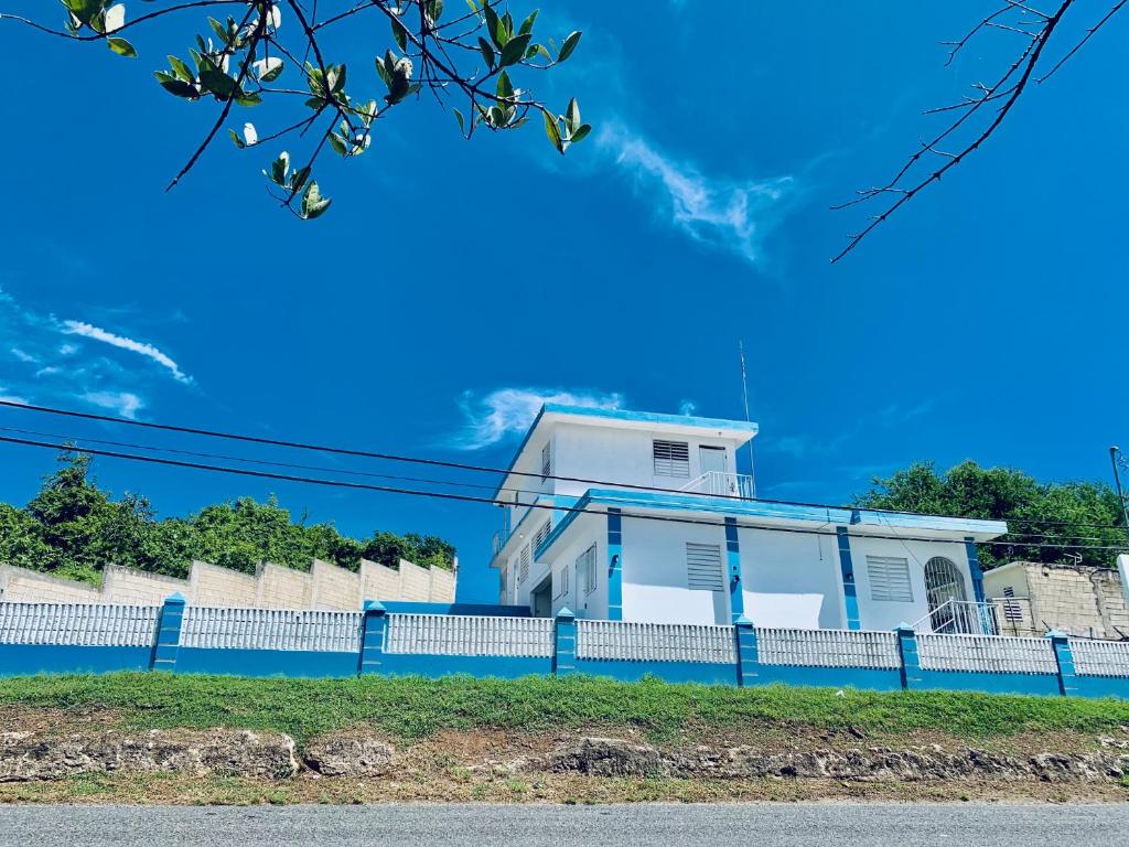 a white house with a blue fence at The Hill Inn at Arecibo 681 Ocean Drive in Arecibo