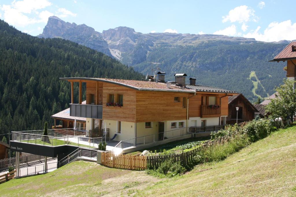 a house on a hill with mountains in the background at Klimahaus Dep. La Fradora in San Cassiano