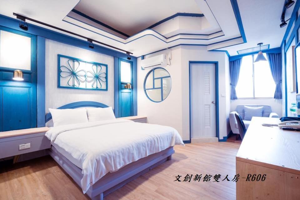 1 dormitorio con 1 cama grande y paredes azules en At Tainan Inn en Tainan